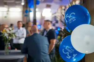 Gäste im Gespräch beim Get-together, blaue Jubiläumsballons „150 Jahre“