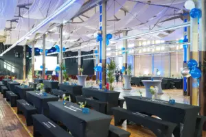 Eingedeckte Tische und Stehtische mit blauen Ballons in der historischen Industriehalle