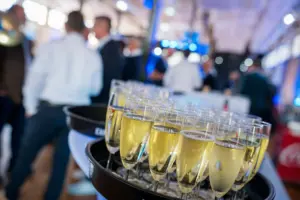 Sektgläser im Vordergrund, Gäste beim Get-together im Hintergrund